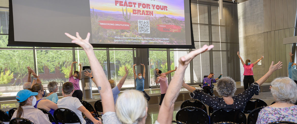 Participants at the inaugural Feast for Your Brain event take part in a group stretch between presentations